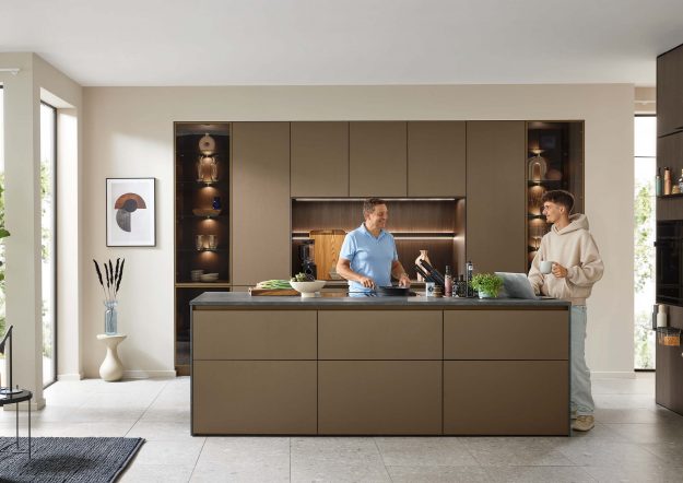 Klassische Inselküche mit braunen Fronten von Ballerina Küchen mit beleuchteten Regalen erhältlich bei KÜCHE kreativ