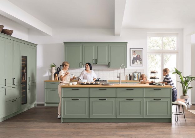 Salbeigrüne Inselküche im Landhausstil von Ballerina Küchen mit Metallgriffen erhältlich bei KÜCHE kreativ